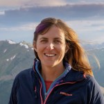 Meg's head and shoulders in front of a beautiful mountain range.