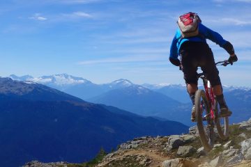 A mountain biker catches some air with the Black Dusk far off in the distance.