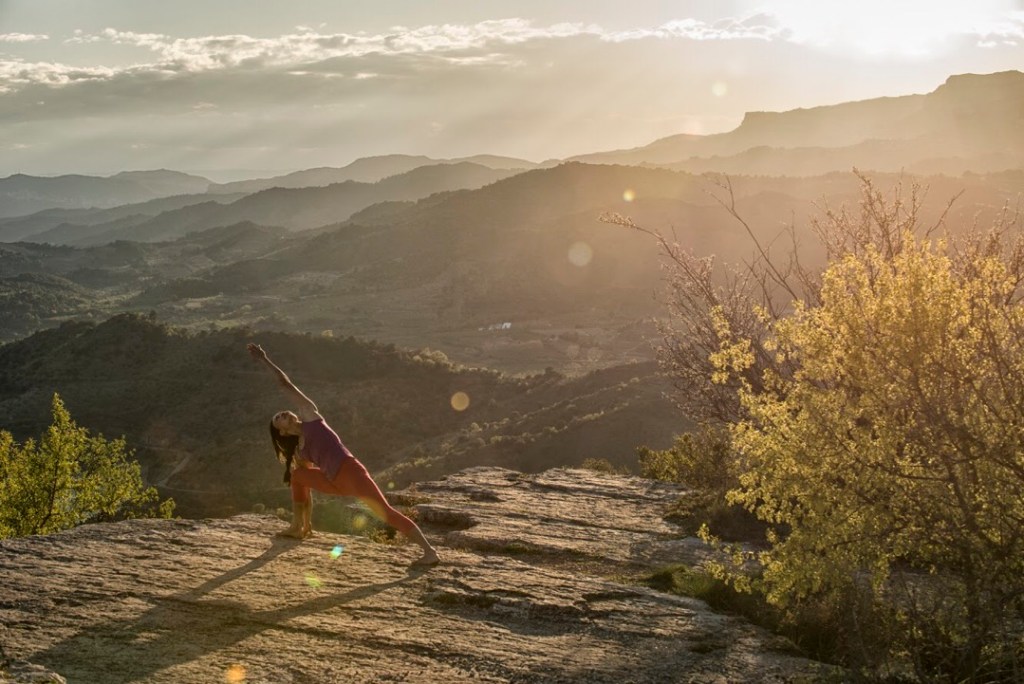 Olivia Hsu practices the Extended Side Angle pose in sunrise light on a rock overlook.