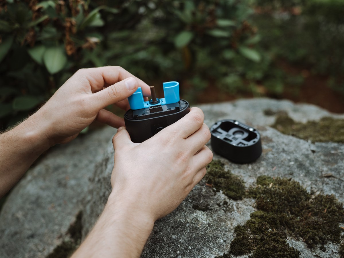 Two hands put the recyclable repellent cartridge into the device.