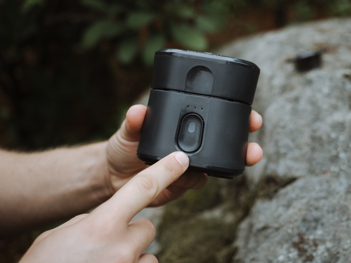 Hands holding the Thermacell Radius, about to press the button.