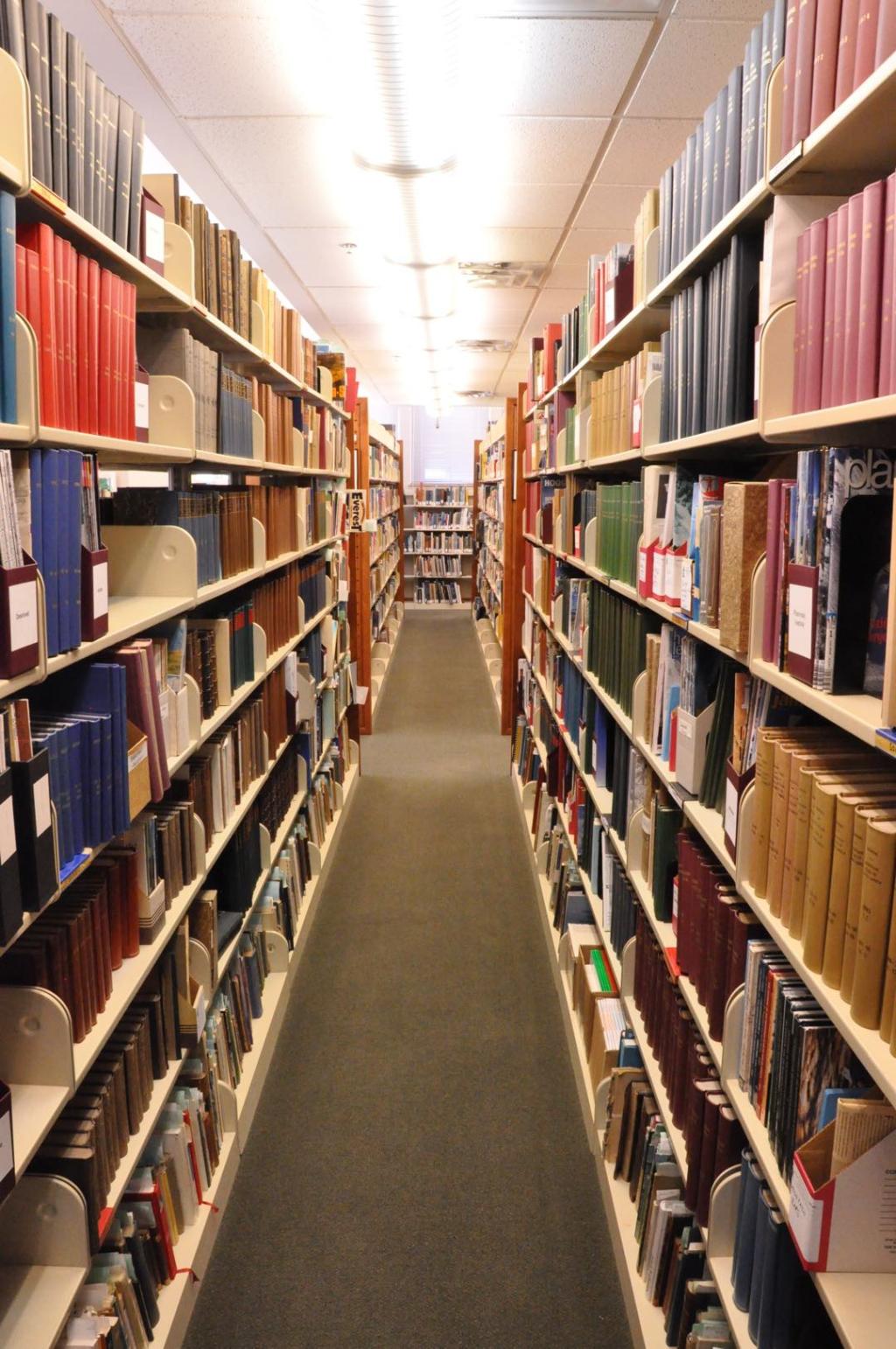 Two long bookshelves stretch down an aisle, covered with books of various colors and shapes.