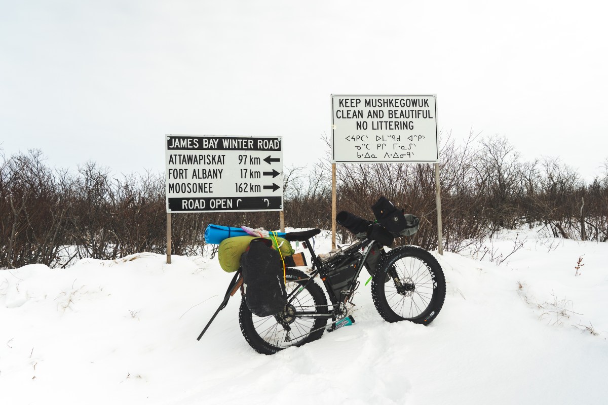 A bike loaded up with gear in front of a road sign.