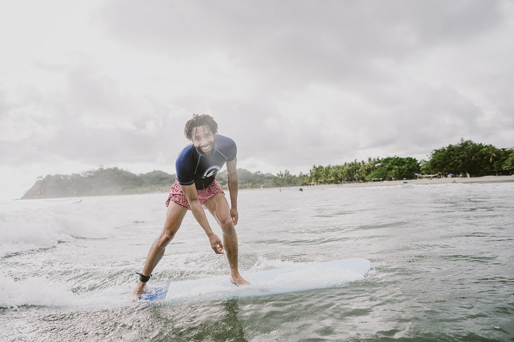 A traveler on an REI Adventures trip surfs a wave.