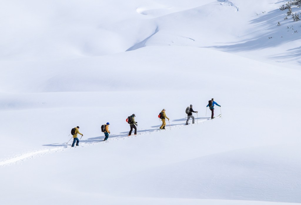 Backcountry skiers skin up the mountain wear bib pants.