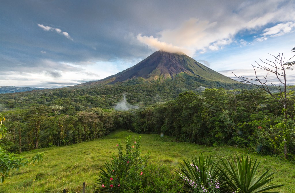 A still-active Arenal Volcano sends wisps of smoke into the sky.