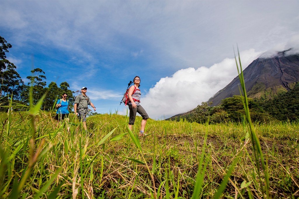 Hikers on an REI Adventures tour enjoy the grand aesthetic of Arenal Volcano National Park.