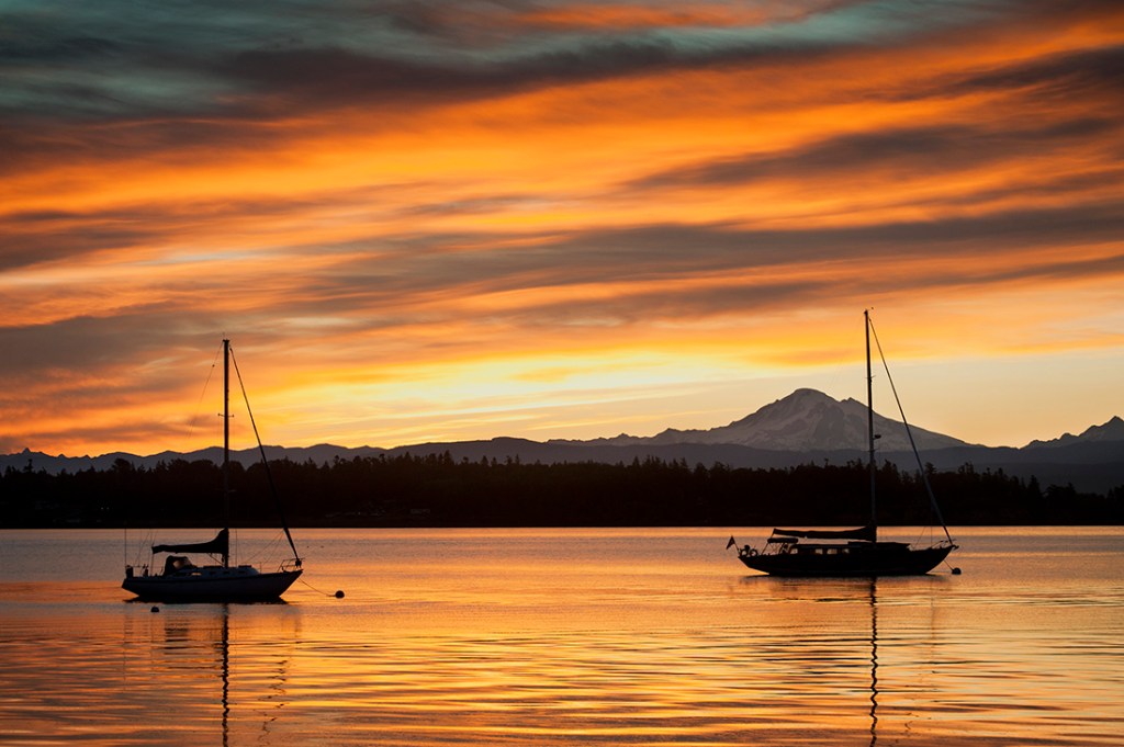 Unmoored sail boats sit idle at sunset.