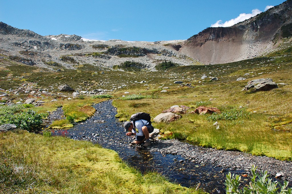 A hiker sips fresh glacial water in the Whistler alpine.
