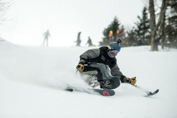 Trevor Kennison uses a sit ski and outriggers to ski down the slope.