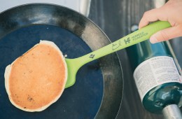 Green Alex Honnold Spatula flipping a pancake in a black pan.