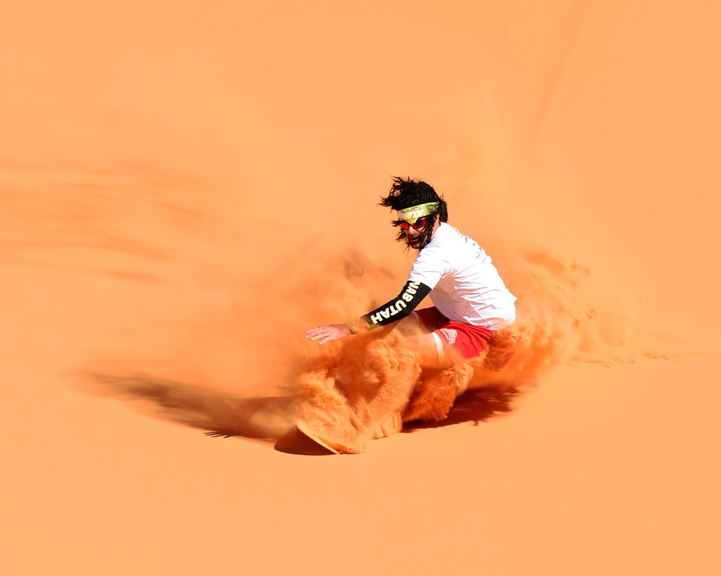 A sandboarder rides pink-hued sand in Utah's Coral Pink Sand Dunes Park.