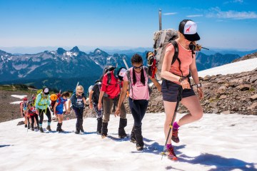 Kids climb a snow-covered mountain as a part of a youth mountaineering course with She Jumps.