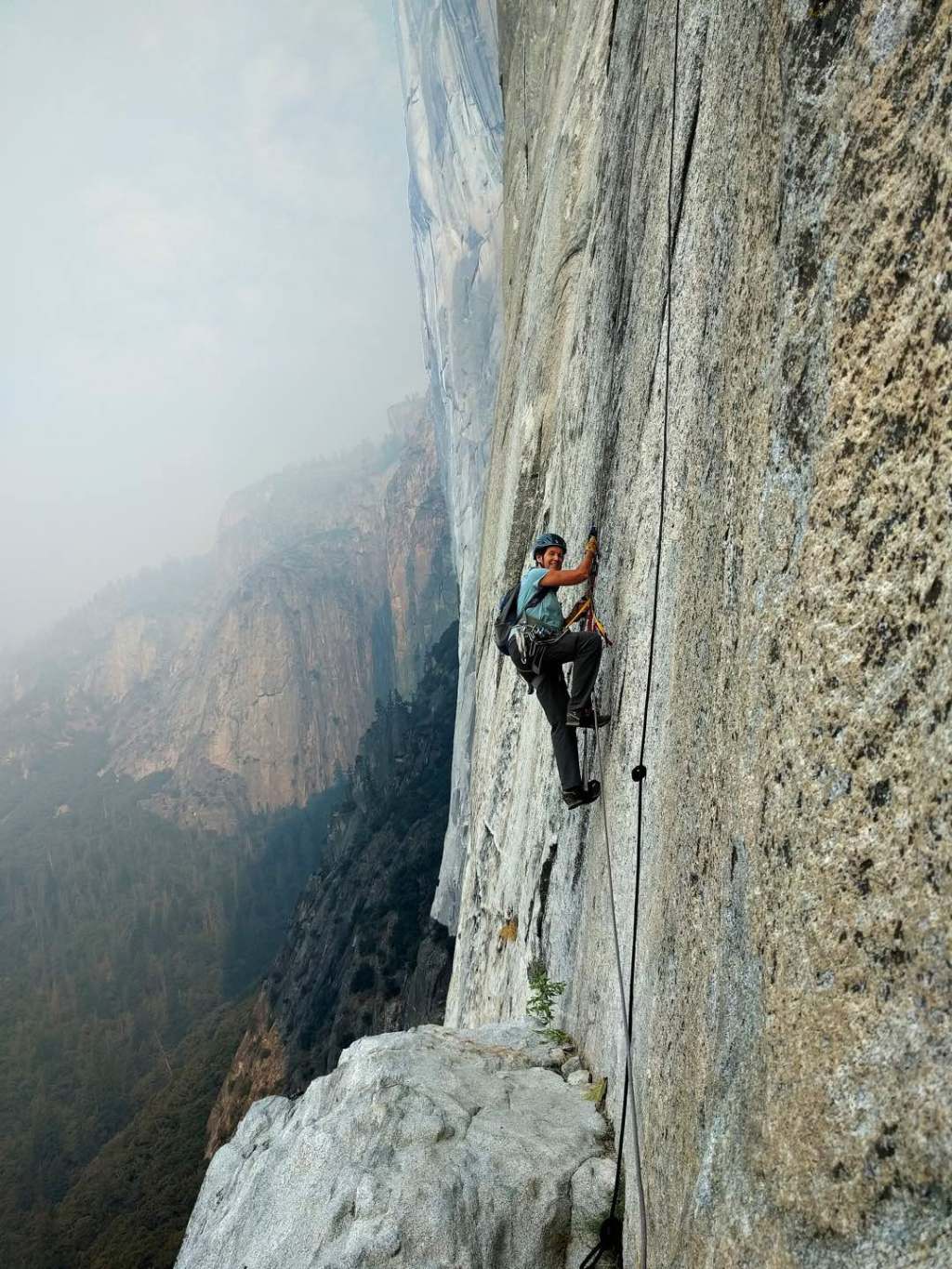 Diedre Wolownick uses jumars to ascend the steep rock face of El Capitan. Behind her, steel rock faces fade into the distance of Yosemite National Park.