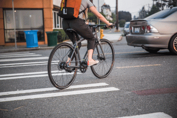 A woman biking in the middle of traffic.