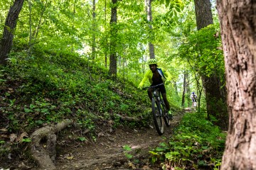 Demonte Cosby rides his mountani bike on a trail through a dense green forest