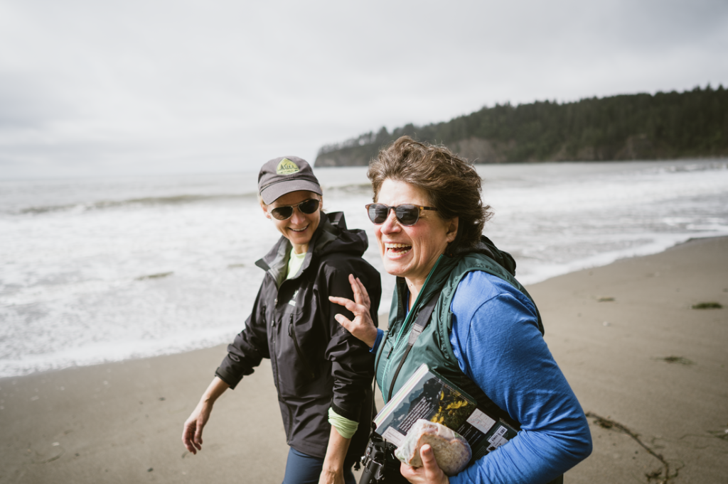 Two hikers laugh, one pushes the other one playfully.