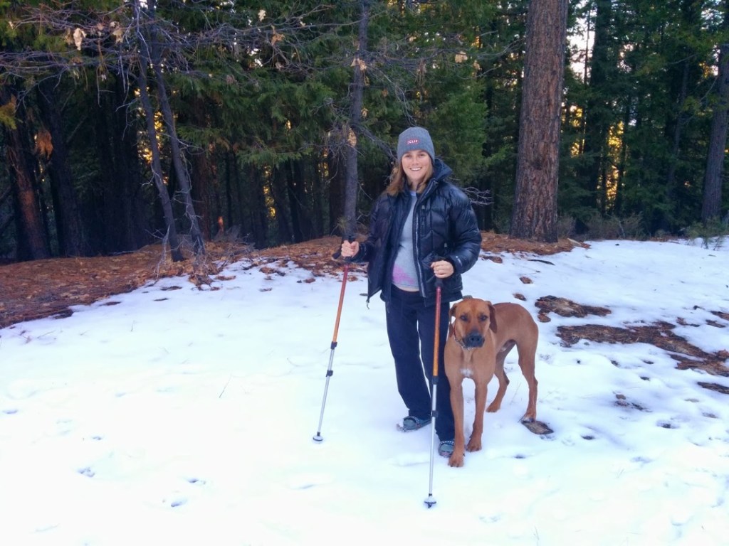 Beth Rodden uses trekking poles as she walks along a snowy path with her dog.