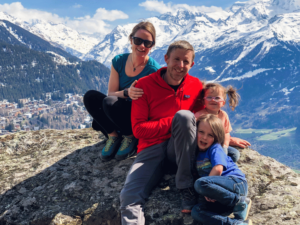 A mom, dad and two kids pose for a photo with smiling faces surrounded by mountains