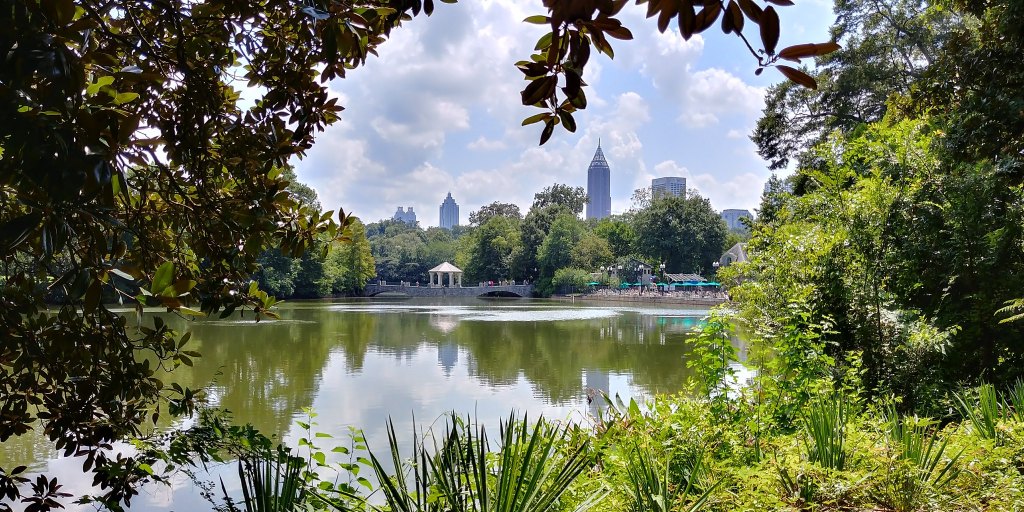 A view of midtown Atlanta skyline over a lake in Piedmont Park.