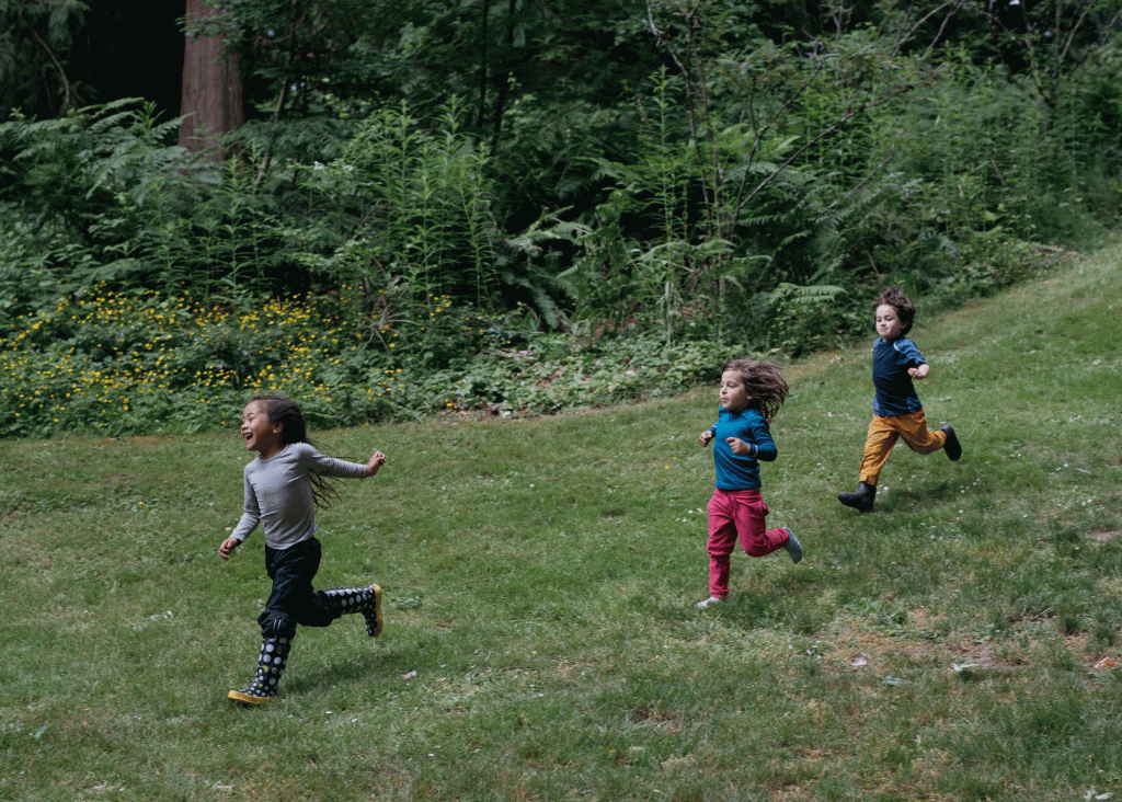 Children sprint through a green meadow