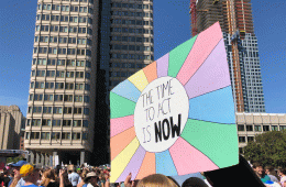 A colorful sign bearing the message "The Time to Act Is Now"