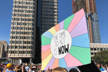 A colorful sign bearing the message "The Time to Act Is Now"