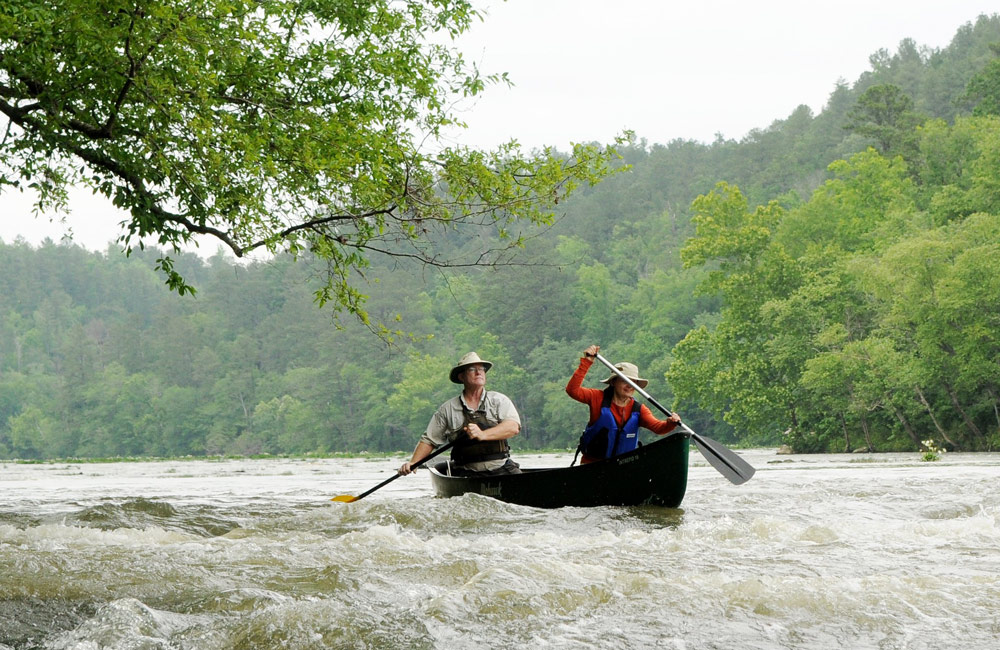 Two paddlers steer a canoe into a rapid. 