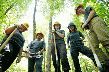 Young women gather around a worksite with shovels in their hands