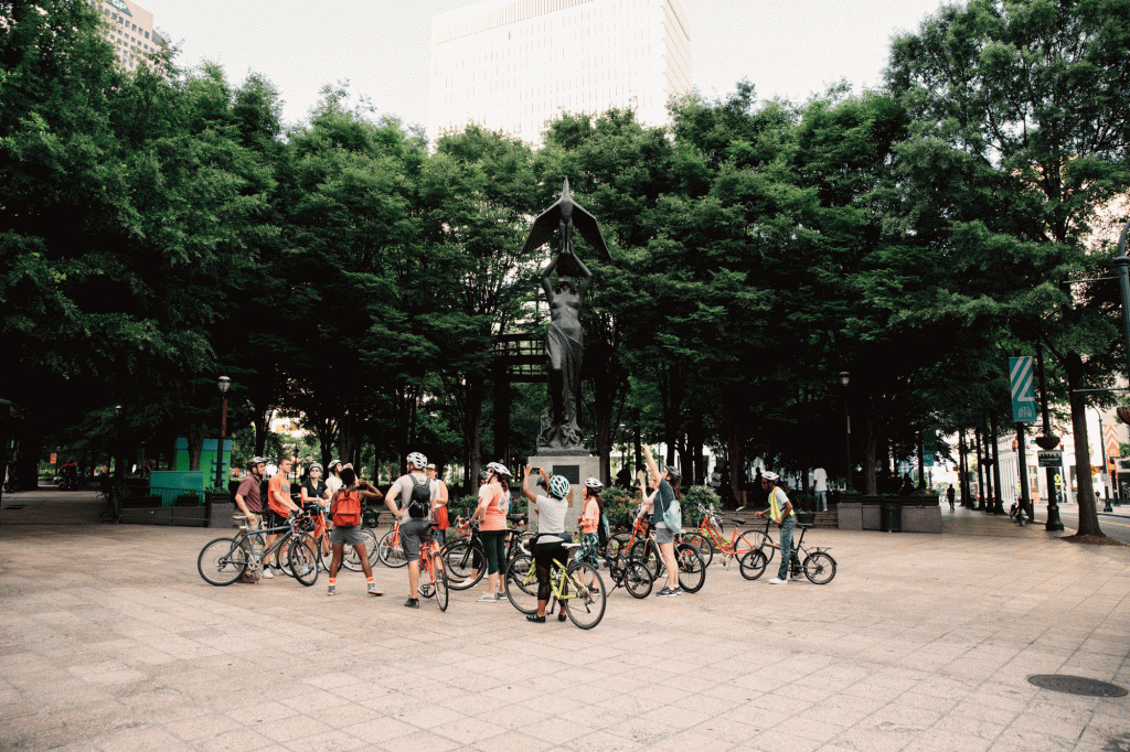 A tour group flanks a statue in urban Atlanta
