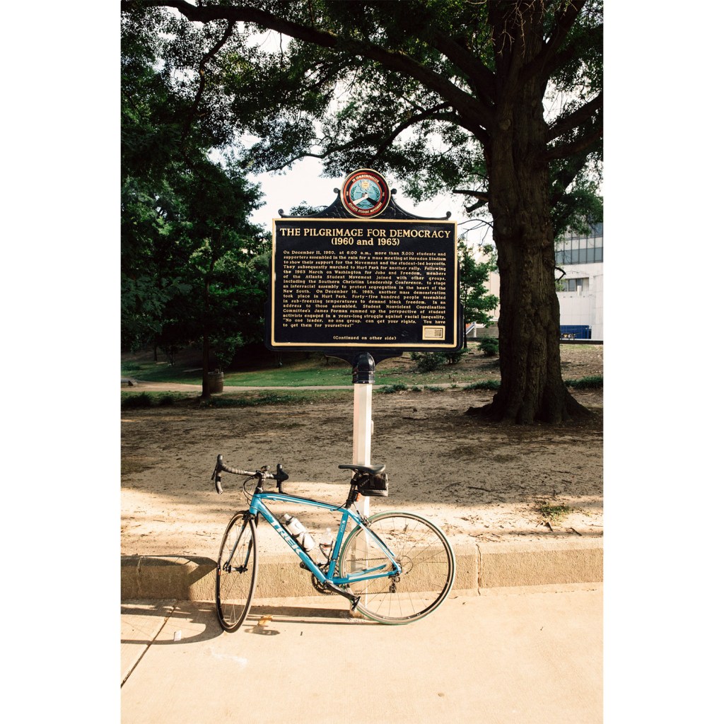 A bike leaning against a historic sign in an urban Atlanta Park