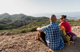 Two hikers sit on a ledge overlooking a hillside outside Los Angeles