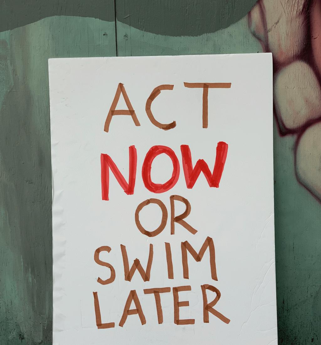 A sign that reads: "Act Now or Swim Later"