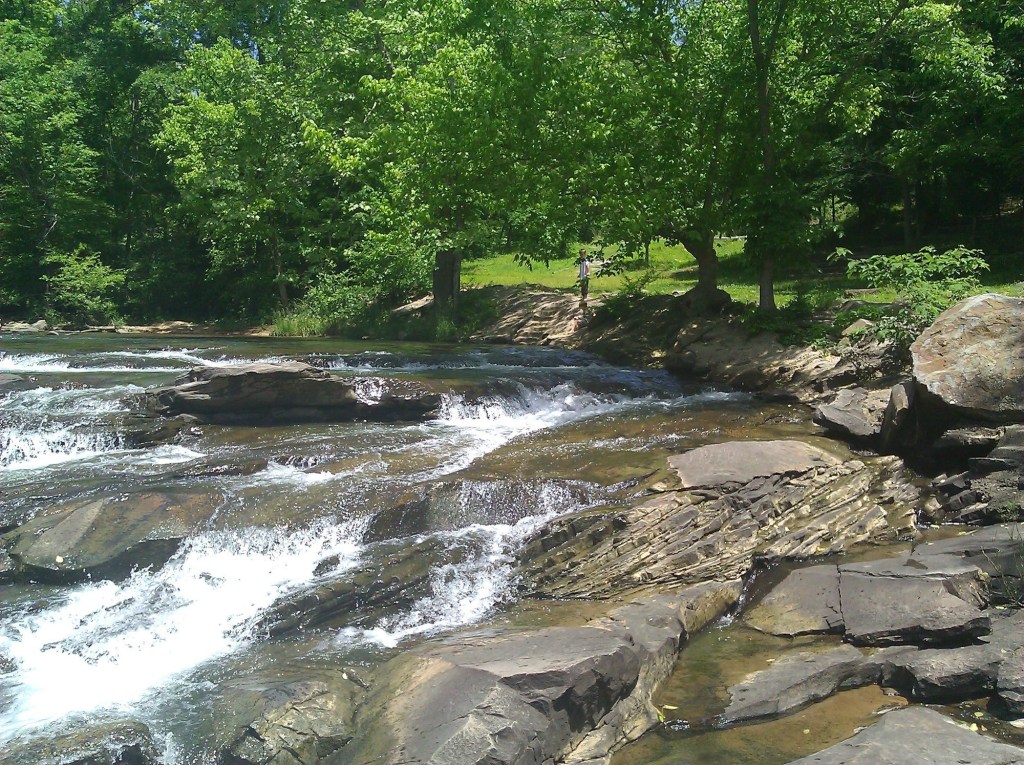 A waterfall with green trees.