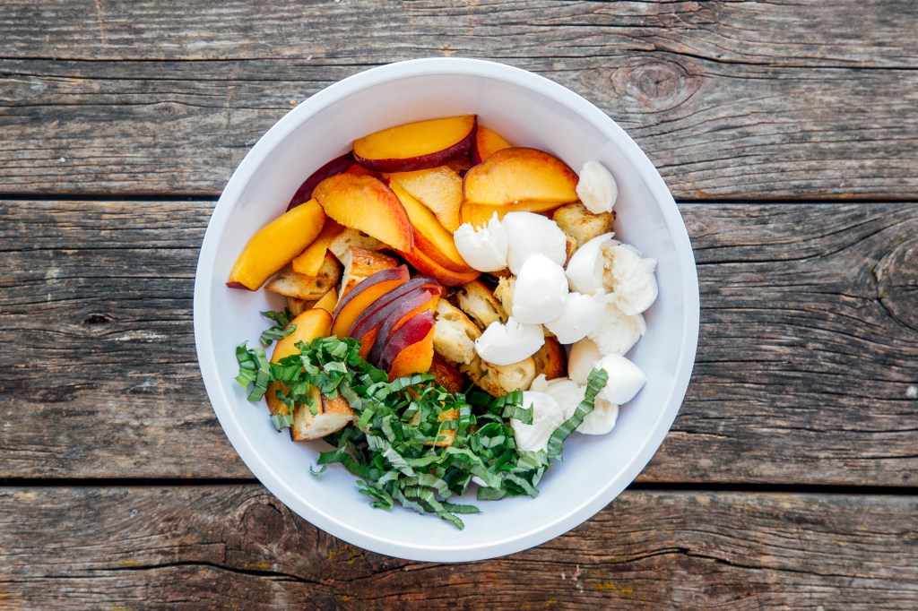 Salad bowl with bread, peaches, basil, and cheese for panzanella salad