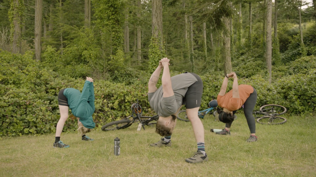 Corepower yoga instructors hold wide-legged standing forward fold chest expansion