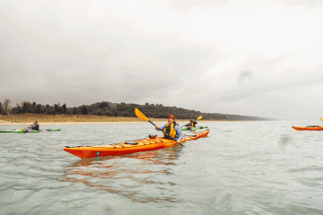 A woman paddles through Lake Michigan with a big smile on her face