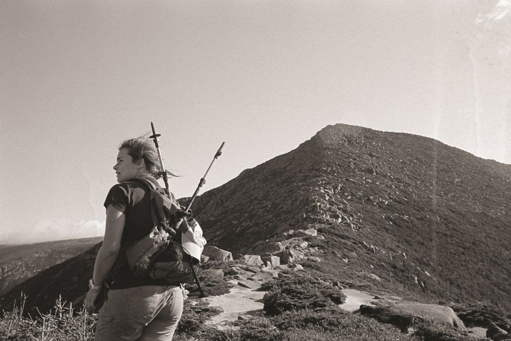 A thru-hiker looks out at the view on a mountain.