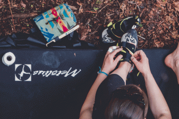A woman prepares to go climbing by tightening her shoes