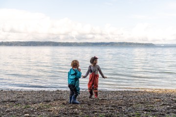 Children play by the water in waterproof overalls