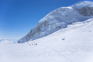 A team of mountaineers hauls gear up a snowy face