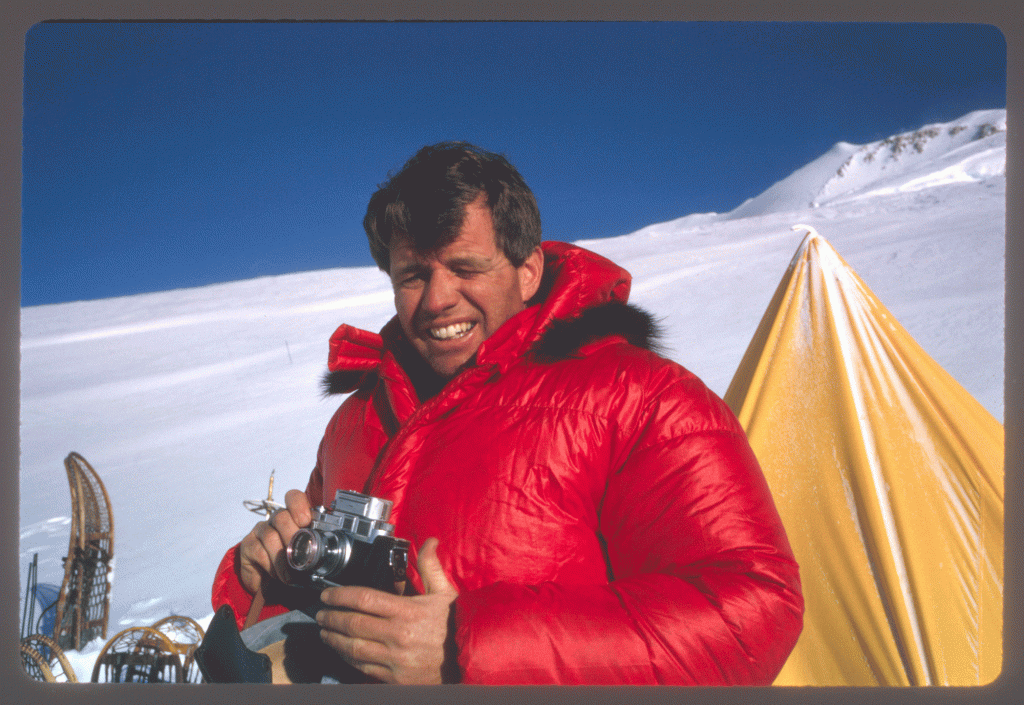 A man holding a camera in a bright-red parka