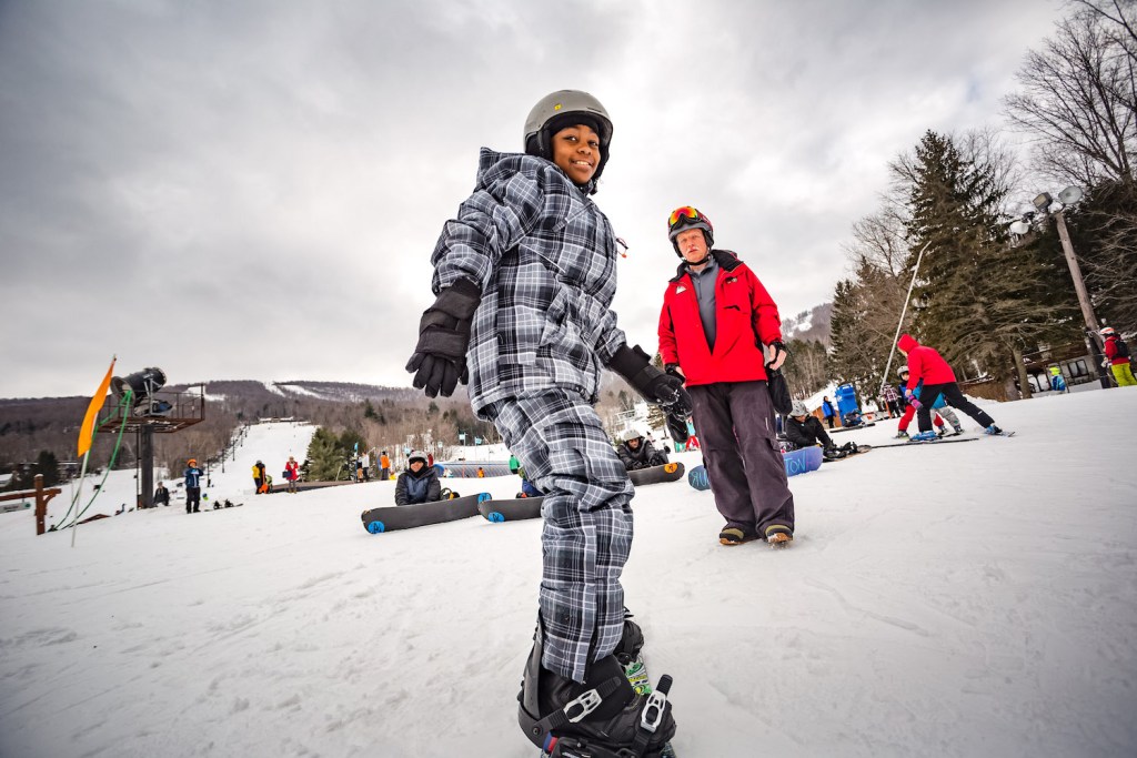 A snowboarder takes a lesson at Windham Mountain.