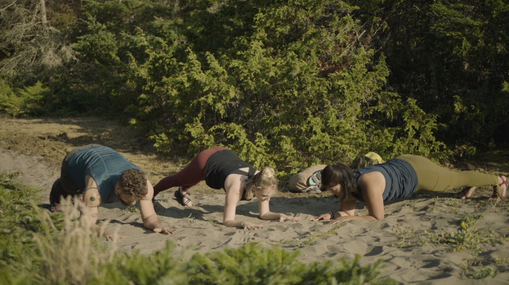 Corepower yoga instructors hold forearm plank, knee to elbow