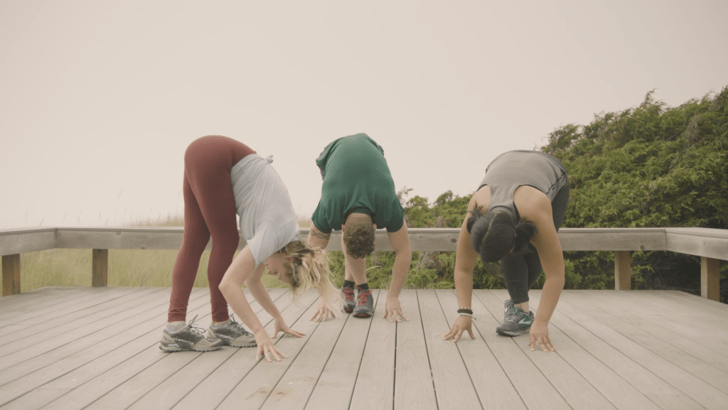 Corepower yoga instructors hold forward fold it band stretch