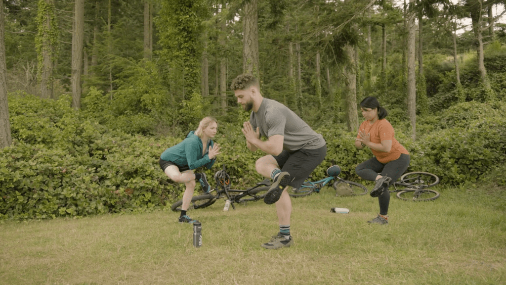 Corepower yoga instructors hold standing half-pigeon quad stretch