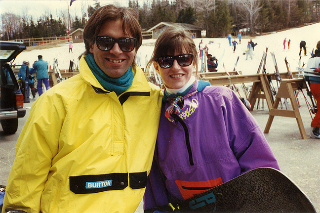 Two snowboarders pose for a photo in vintage '80s apparel.