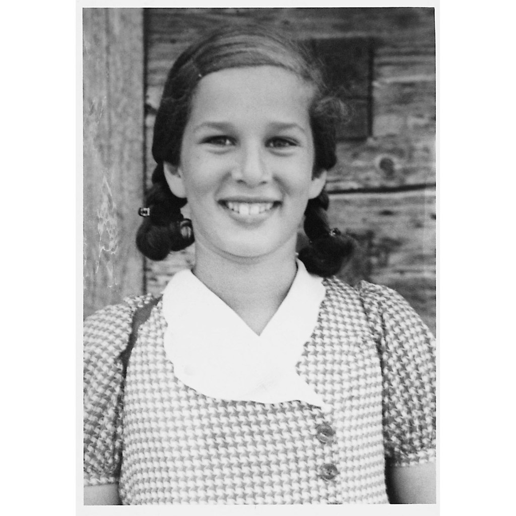 Gert Boyle stand in front of a wood building as a young girl