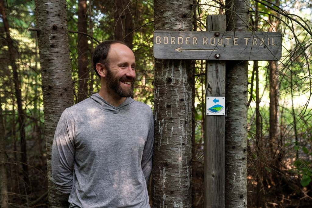 Ultrarunner Alex Falconer stands next to a tree in the Boundary Waters Wilderness.