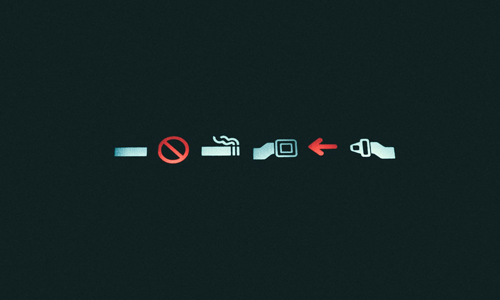 No smoking and seat belt on illuminated signs on an airplane.